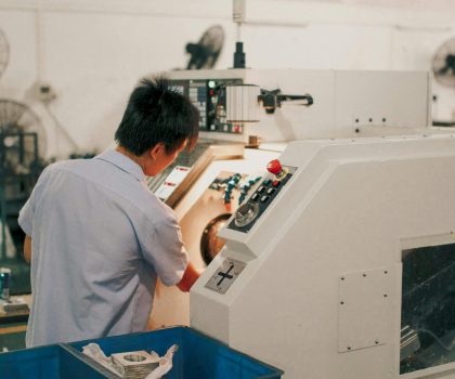 Worker focusing on operating industrial machinery in a factory setting.